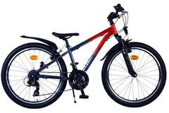 Jongen op rode/grijze Volare XC Race 24 inch kinderfiets met 21 versnellingen, handremmen, reflectoren en comfortabel zadel